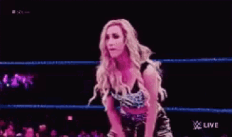 a woman is dancing in a wrestling ring with a live sign in the corner