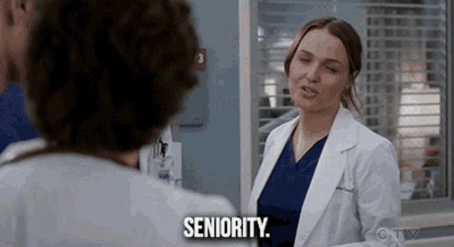 a woman in a lab coat says " seniority " in front of a man