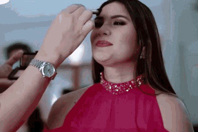 a woman in a red dress is getting her makeup done