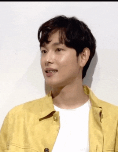 a young man wearing a yellow jacket and a white t-shirt