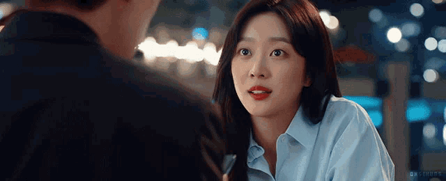 a woman in a blue shirt is looking at a man in a suit