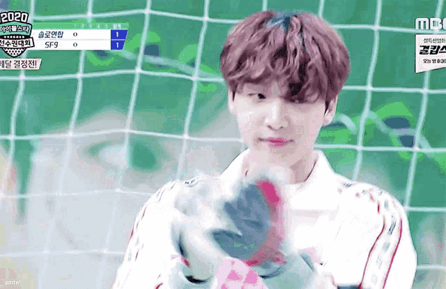 a young boy is holding a soccer ball in front of a soccer net .