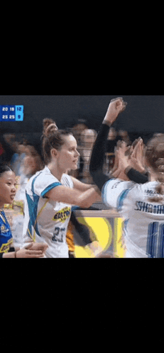 a group of female basketball players are giving each other a high five .