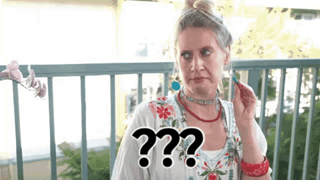 a woman is sitting on a balcony with a question mark in front of her .