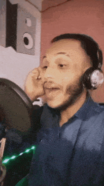 a man wearing headphones and a blue shirt singing into a microphone