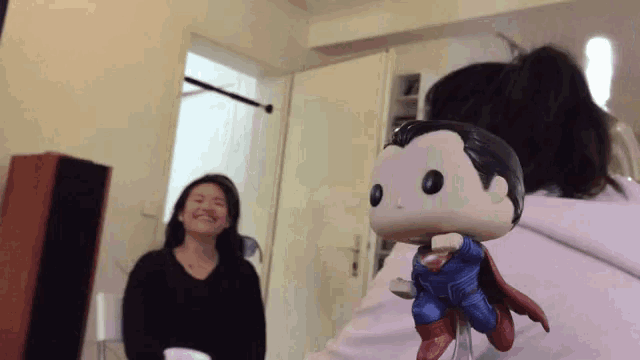 a funko pop of superman is being held by a woman