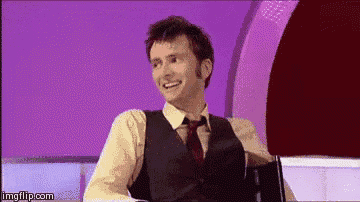 a man in a vest and tie is smiling while sitting in front of a purple background .