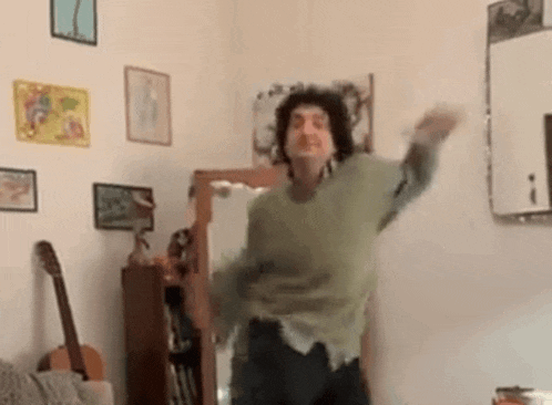 a man in a green sweater is dancing in a room .