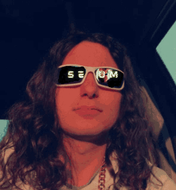 a man with long curly hair wearing sunglasses with the letters s and m on them