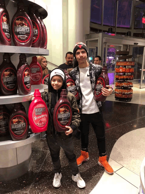 two boys holding bottles of hershey 's syrup