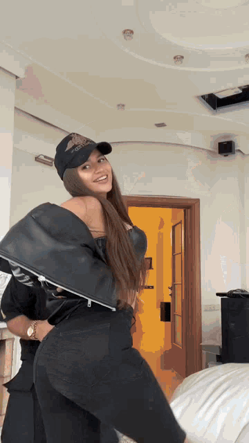 a woman wearing a black hat and black pants is standing in front of a door