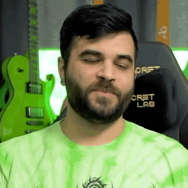 a man with a beard wears a green tie dye shirt that says cret lab on it