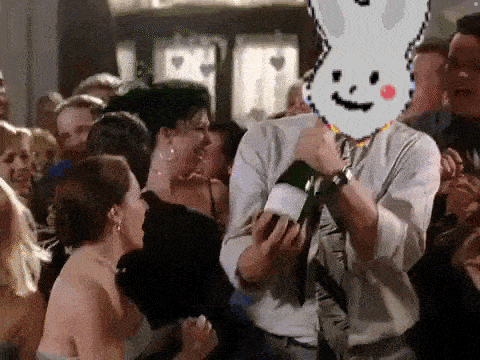 a man is holding a bottle of champagne in front of a crowd of people with a pixelated bunny on his face .