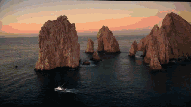 a boat is in the water near some rocks in the ocean