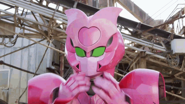 a pink robot with green eyes and a heart on its chest