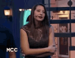 a woman is standing with her arms crossed in front of a mcc logo
