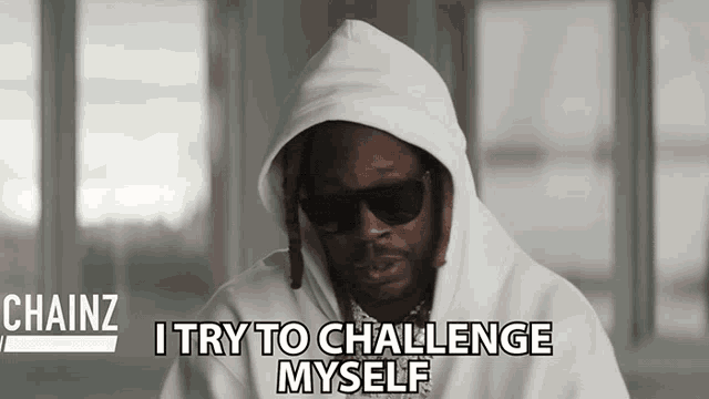 a man in a white hoodie and sunglasses says " i try to challenge myself "