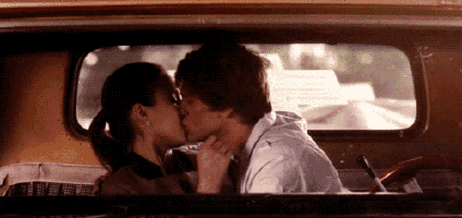 a man and a woman are kissing in the back of a truck .