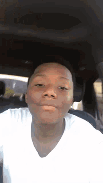 a young man in a white shirt is sitting in the back seat of a car .