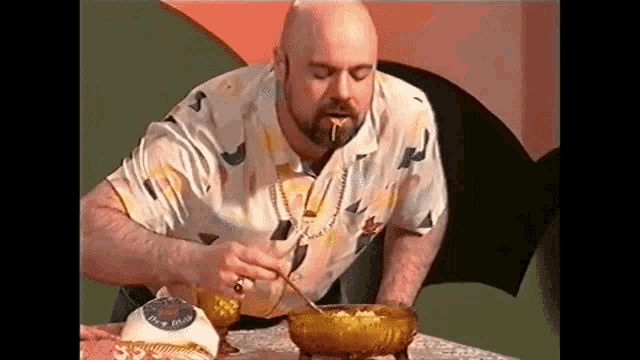 a bald man with a beard is eating cereal from a bowl with a spoon .