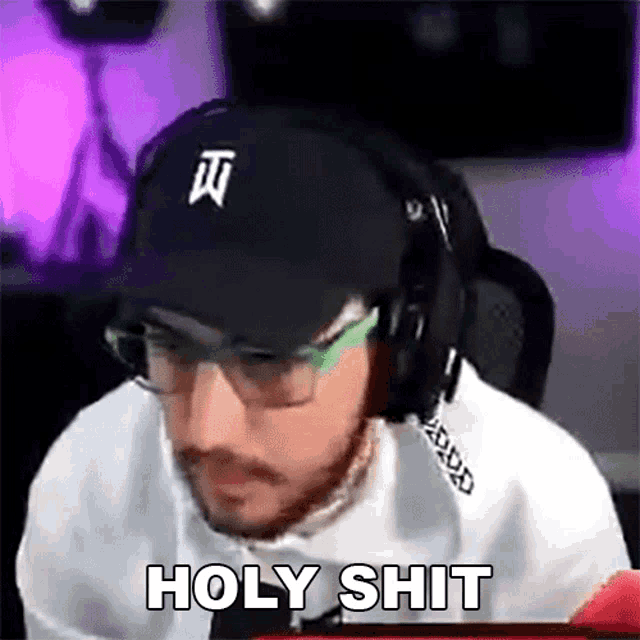 a man wearing a hat and headphones is sitting in front of a computer screen .
