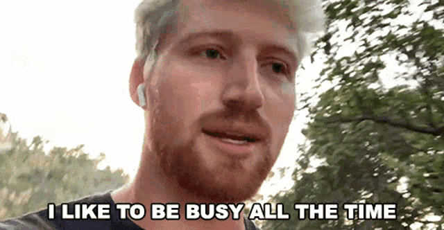 a man with a beard is wearing ear buds and says i like to be busy all the time