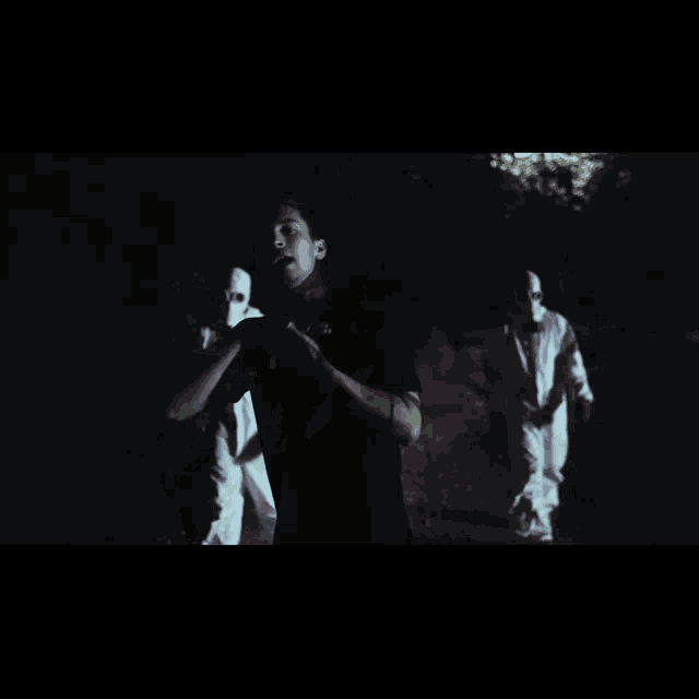 a man in a black shirt is standing in the dark in front of a ghost .