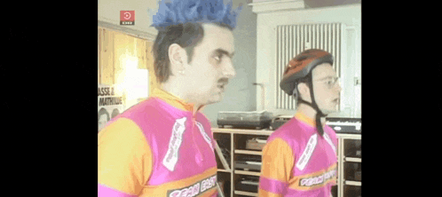a man with a mohawk wearing a helmet and a pink and orange shirt that says ' good day ' on it
