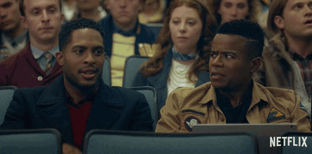 a group of people sitting in a theatre with a netflix logo on the bottom of the screen
