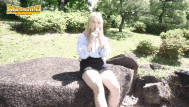 a woman sits on a rock in a park in front of a sign that says matsumoto