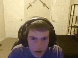 a young man wearing headphones is sitting in front of a wall with two swords on it .
