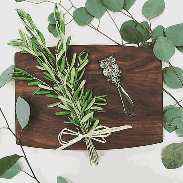 a wooden cutting board with a bunch of leaves and an owl spoon