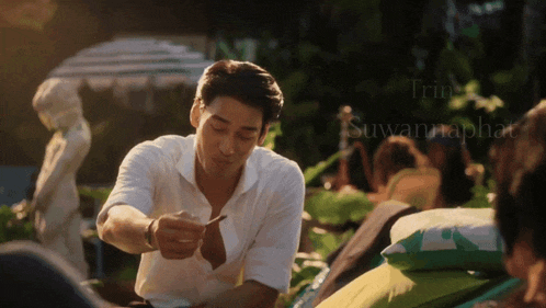 a man in a white shirt is holding a spoon in his hand in front of a sign that says suwanraphael