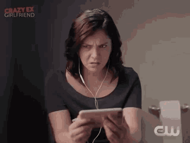 a woman is sitting on a toilet looking at a tablet .