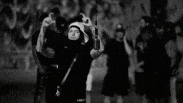 a black and white photo of a man wearing a mask and a hat with a microphone hanging from it