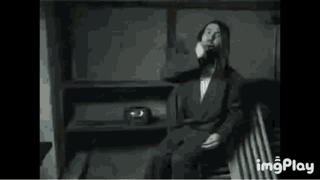 a man with long hair and a beard is sitting on a bench .
