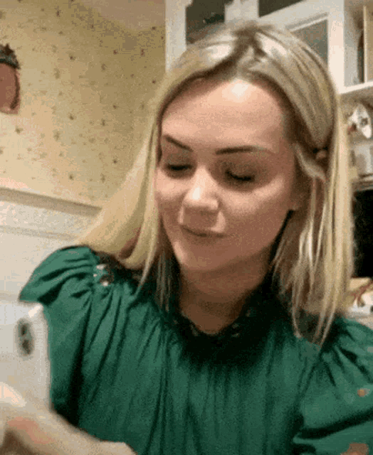 a woman in a green shirt looks at her phone