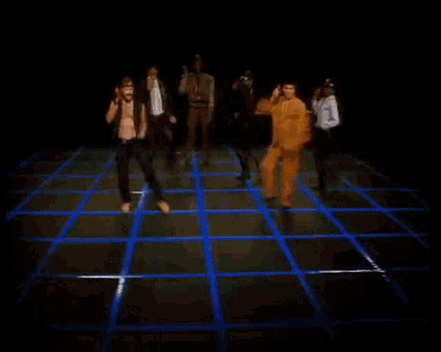a group of men are dancing on a stage with blue lights .