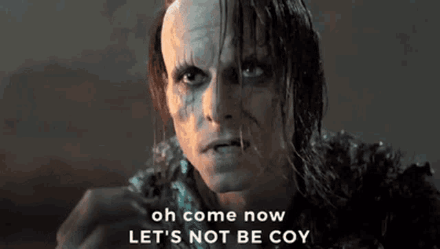 a close up of a man 's face with the words `` oh come now let 's not be coy '' written above him .
