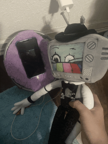 a stuffed toy that looks like a television is being held by a hand