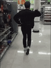 a man is dancing in a store while walking down the aisle .