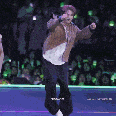 a man in a brown jacket is dancing on a stage in front of a crowd