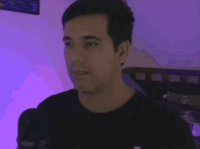 a man in a black shirt is standing in front of a microphone in a room .