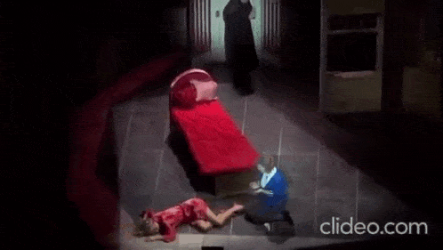 a man is kneeling down next to a woman laying on the floor next to a bed .