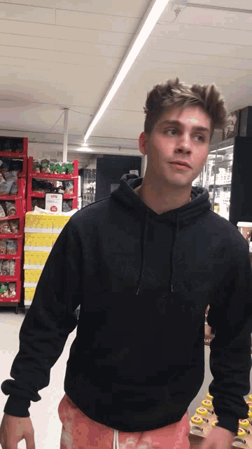 a man in a black hoodie stands in a store