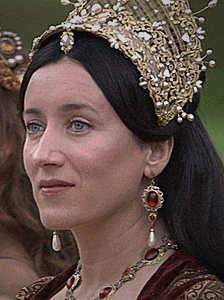 a woman wearing a crown and earrings looks to the side
