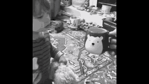 a black and white photo of a child holding a cup with a hedgehog on it