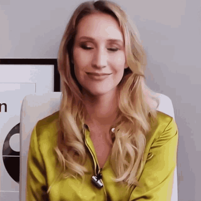 a woman wearing a yellow shirt is smiling and looking down
