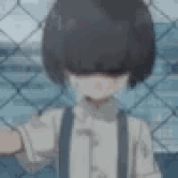 a boy is standing in front of a chain link fence with his hand out .