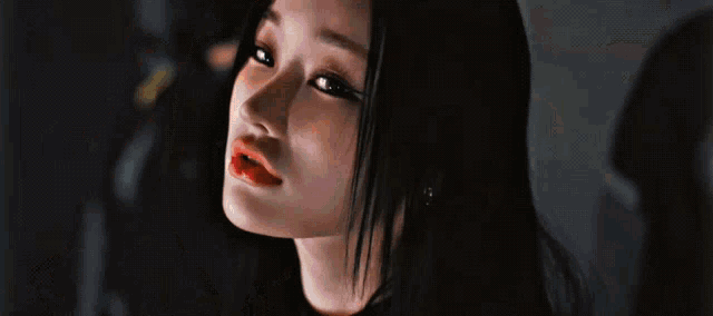 a close up of a woman with long black hair and red lips